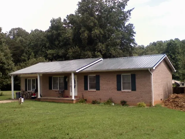 Gray metal roof on a brick ranch house with a side carport in Roxboro