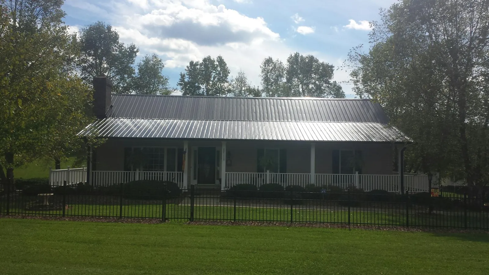 Gray metal roof on a brick ranch with a full width front porch — Gutter Guard Installation work by our crew in Roxboro