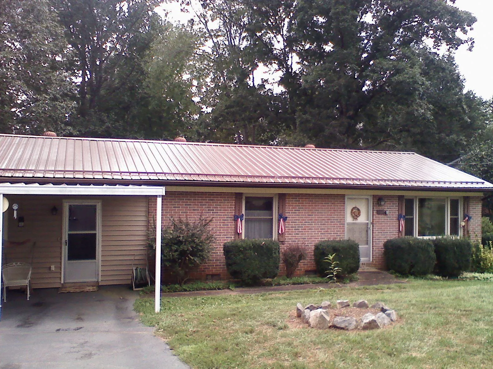 Bronze metal roof and carport on a brick ranch home — Roof Repair work by our crew in Roxboro