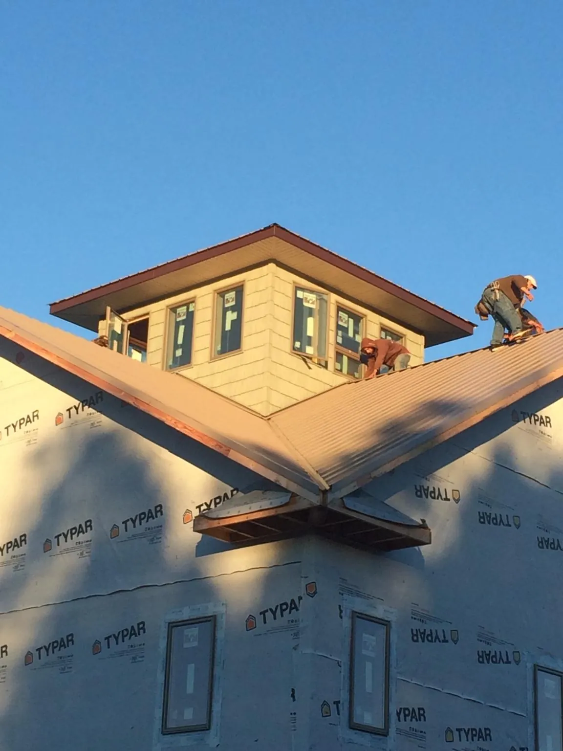 Roofers working around a rooftop cupola on a new metal roof at sunset — Roof Waterproofing in Roxboro by Roofing Brothers
